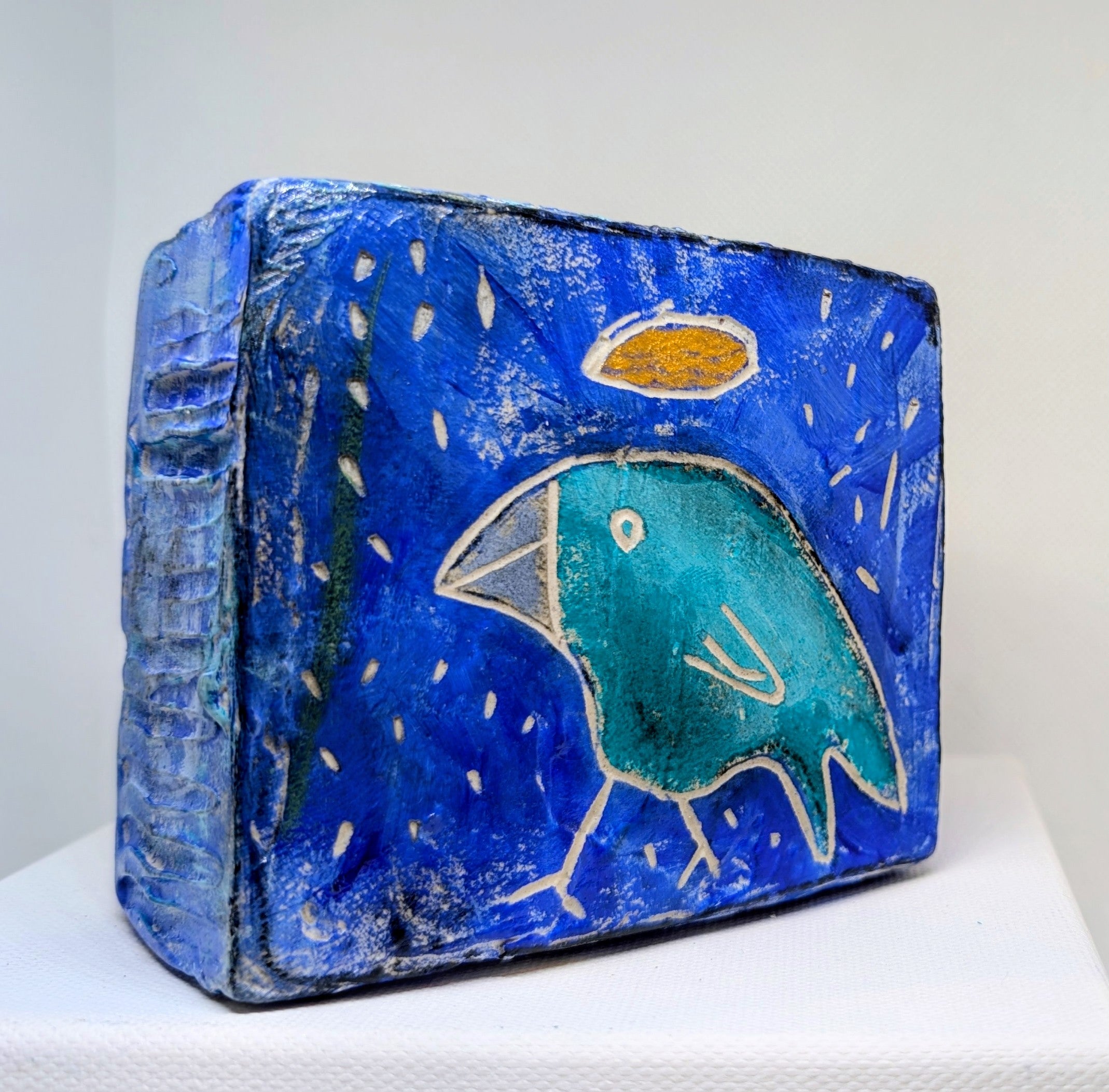 Blue bird icon:  Textured bird painted block on upcycled material