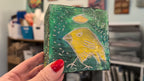 Yellow bird icon:  Textured bird painted block on upcycled material